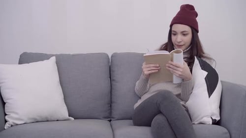 Woman Comfortably Reading Book on Couch in Home