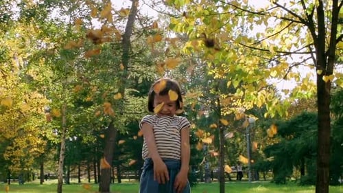 Happy Child Throws Leaves in Autumn Park