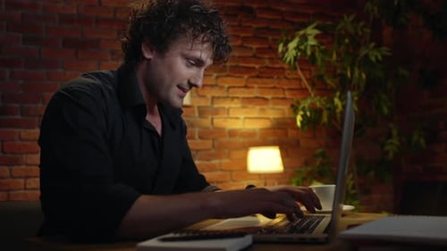 Jeune homme d'affaires prospère souriant travaillant au bureau la nuit