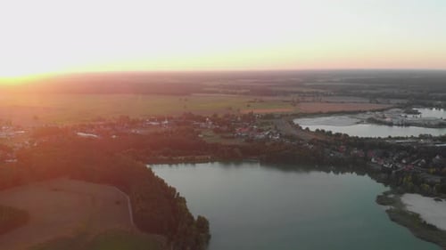 Cinematic Aerial Shot of Lake and Lush Green Fields During Sunset