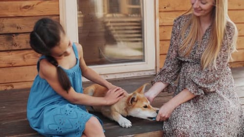 Glückliche Mutter und Tochter streicheln Lovely Puppy Outdoor