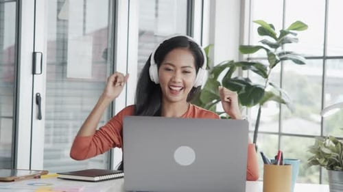 Excited Woman Dancing with Headphones at Desk