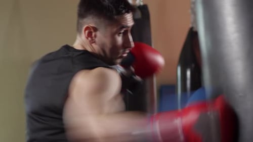 Strong Boxer Hitting Heavy Bag in Gym