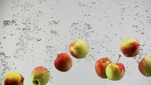 Fresh Colorful Apples Falling in Splash of Water with Air Bubbles
