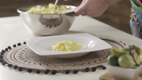 Hands Serving Cooked Farfalle Pasta on a Plate