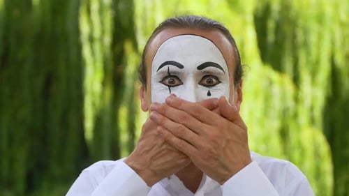 Mime on the Park zeigt Pantomime. Mime schließt den Mund mit den Händen