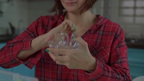 Woman Recycles Plastic Water Bottle in Kitchen