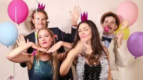 Group of young friends having a great time in party photo booth