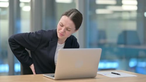 Young Woman with Back Pain at Office Desk