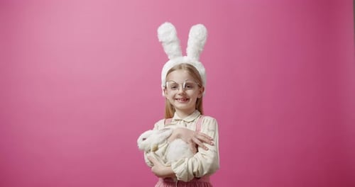 Happy Child Hugging a Rabbit on Pink Background