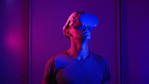Man Wearing VR Headset in Neon Lit Room