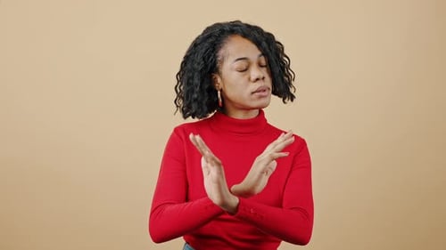 Junge emotionale Afroamerikanerin trägt roten Pullover, gestikuliert STOP zur Kamera und spricht Nein