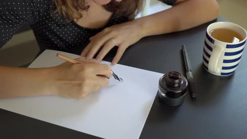 Close Up Shot of Young Woman in a Christmas Hat Calligraphy Writing on a Paper Using Lettering
