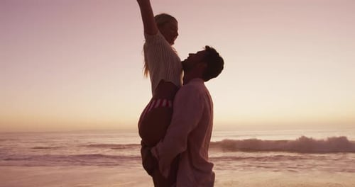 Caucasian couple enjoying time at the beach during the sunset