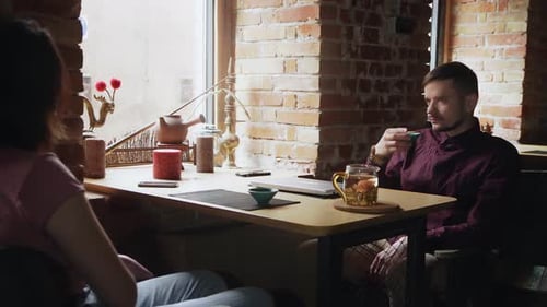 Young Diverse Couple Smiling and Speaking While Drinking Tea on Date in Cafe