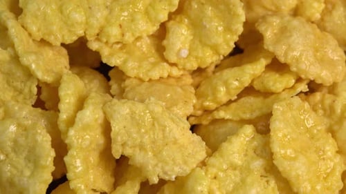Crispy corn flakes rotating close up, dry healthy breakfast. Honey cornflakes for healthy cereal