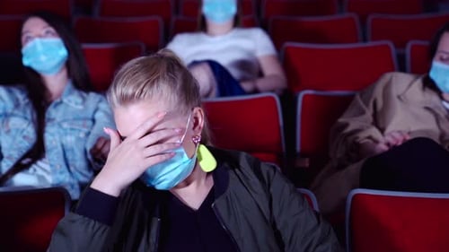 Masked Woman Watching Movie in Dark Theater