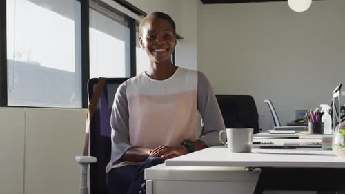 Smiling Woman Sitting at Desk in Modern Office