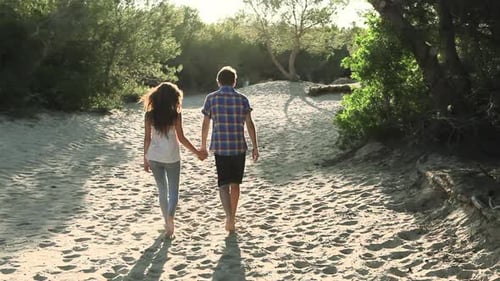 Romantic Couple Walking Hand-in-Hand Along Sandy Beach