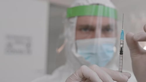 Medical Worker Holding Needle in Protective Gear
