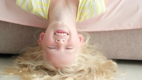 Smiling Child with Blond Curly Hair Upside Down