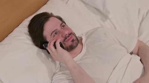 Man Talking on Cell Phone in Bed