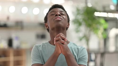 Young Man Prays with Hands Clasped Together
