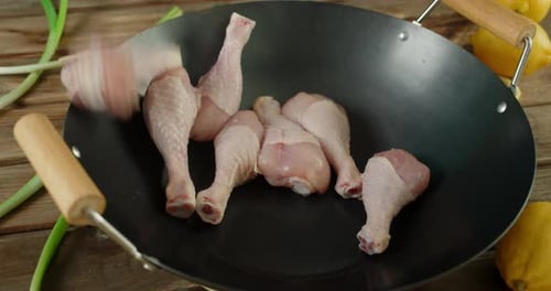 Raw Chicken Drumsticks Falling Into Wok