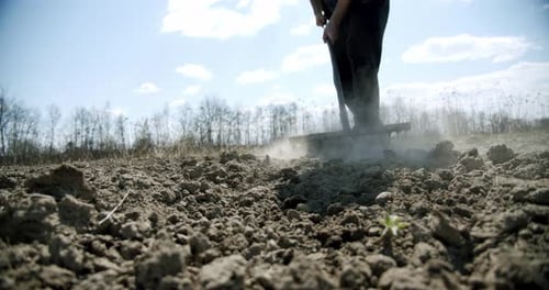 Farmer arbeitet Harke auf dem Boden, lockert den Boden. Hoeing-Feld. Zeitlupe. Nahaufnahme