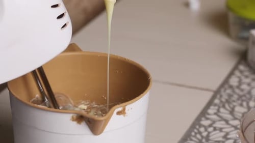 Eine Frau fügt der Buttercreme Kondensmilch hinzu. Für einen Kekskuchen mit Kekskrümeln. Nahaufnahme.