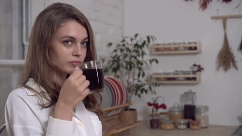 Woman Drinking Coffee in a Bright Kitchen