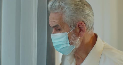Senior Man Wearing Mask Indoors by Window