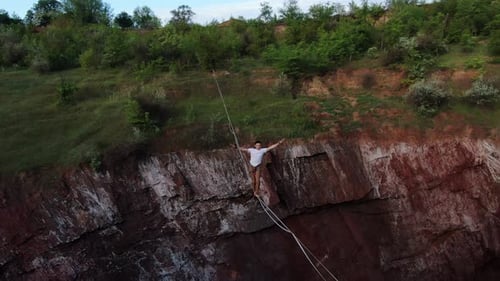 Man Tightrope Walking Across a Canyon in Wilderness