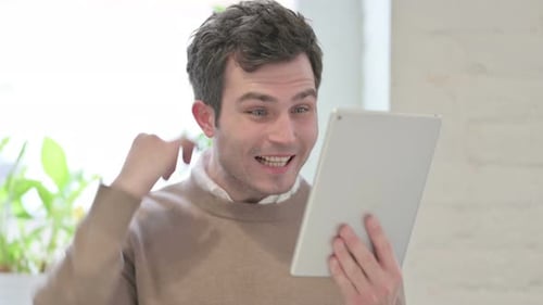 Portrait of Man Celebrating on Tablet in Office