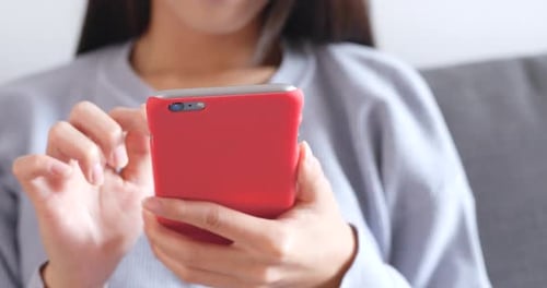 Woman Using Red Smartphone While Sitting at Home