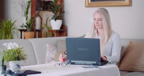 Businesswoman Working on Laptop on a Project at Home Office. Young Woman Using Laptop.