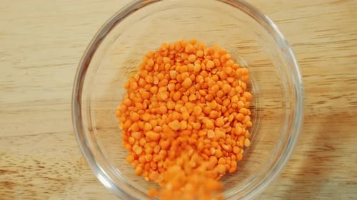 Red Lentils Falling Into Glass Bowl, Close Up