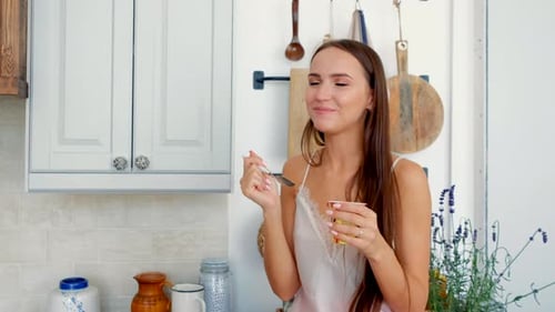 Young Woman Eating Yogurt in Farmhouse Kitchen