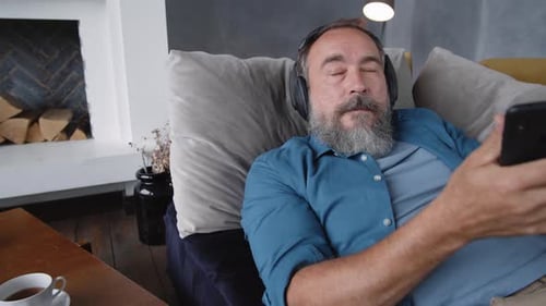 Senior liegt auf der Couch und hat eine Schalltherapie