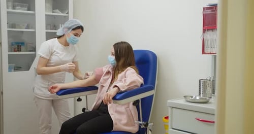 Medical Worker Tending Patient in Clinical Setting