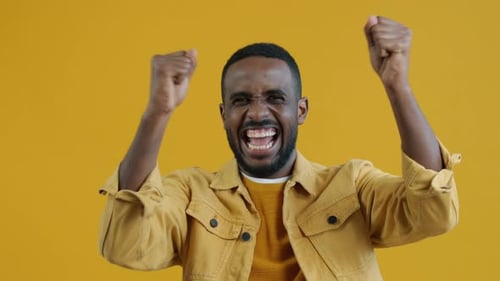 Ecstatic Man Celebrates Success Against Yellow Background