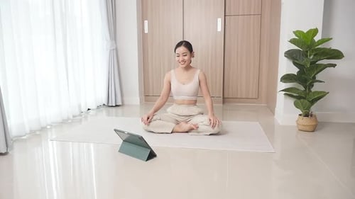 Frau studiert Online-Meditation auf dem Boden im Wohnzimmer, um die Nachteile zu verbessern