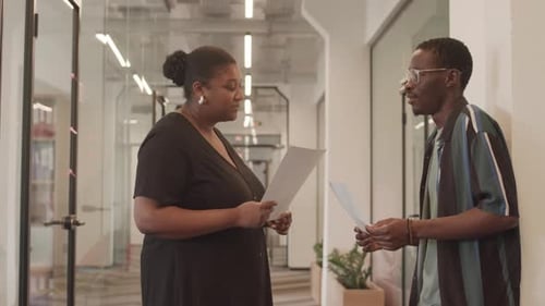 Two Coworkers Talking in Modern Office Setting