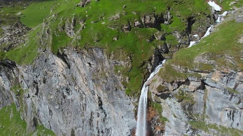 Aerial: drone flying over scenic waterfall and mountain stream on the italian Alps