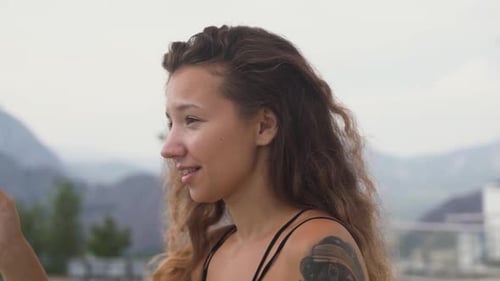 Woman Looks Through Binocular Telescope at Mountains