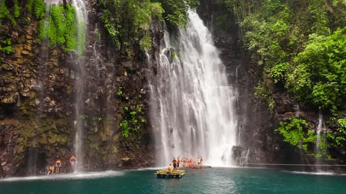 Lush Waterfall with People on Bamboo Raft
