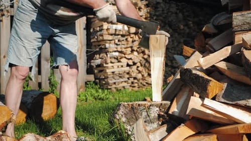 Strong Male Worker Chopping Wood Swinging and Hitting Wooden Log with Axe