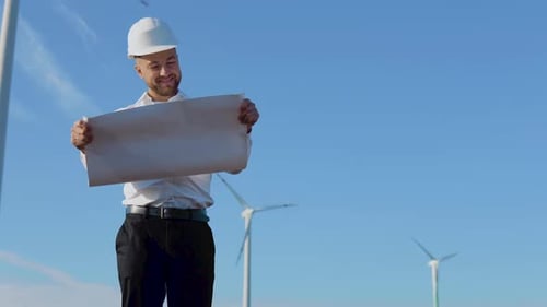 A Male Engineer in a White Helmet and a Classic Shirt Inspects the Power Plant's Capacity and Reads