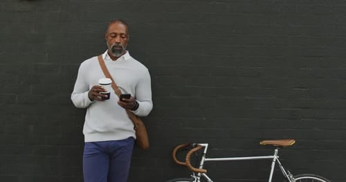 Stylish Man with Bicycle Holds Coffee and Phone