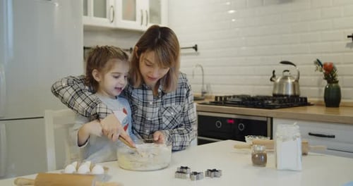 Mother and Daughter Baking Cookies Together in Kitchen